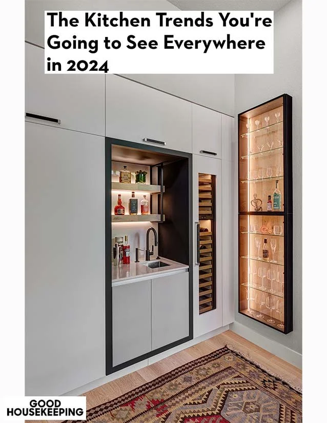 Modern kitchen bar setup with a small sink, open shelves with bottles, a glass display case with glassware, and a built-in wine rack, with a colorful rug on the floor.