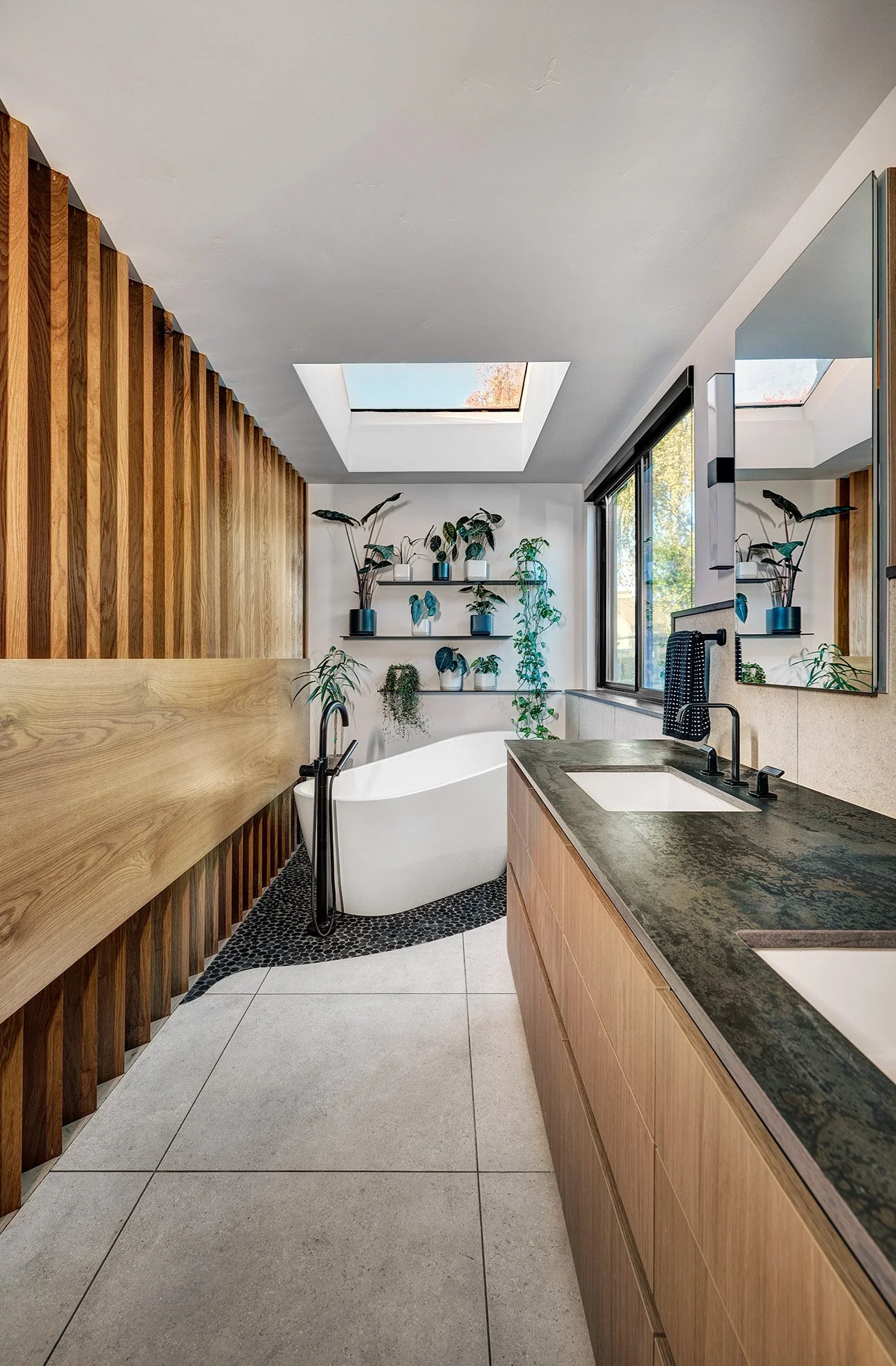 Primary bathroom remodel with slatted wall, European laminate channel cabinets, freestanding tub on pebble tile floor