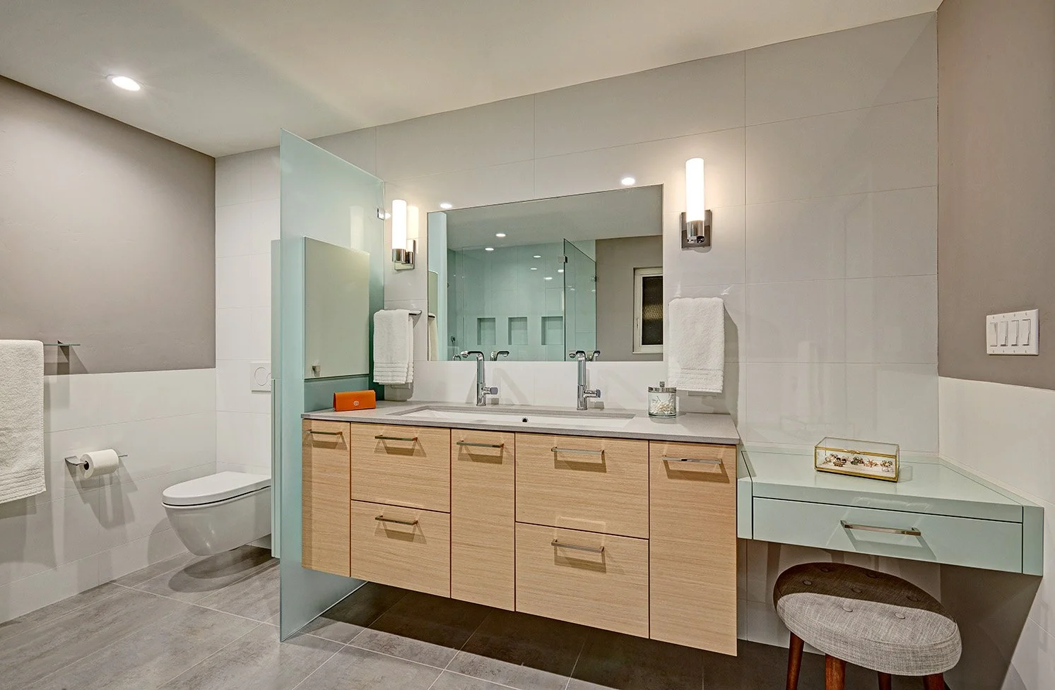 Modern primary bath remodel, laminate cabinetry, glass toilet enclosure, makeup station