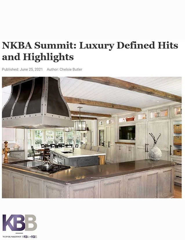 Interior of a rustic kitchen with white cabinets, wooden beams, and a large kitchen island.