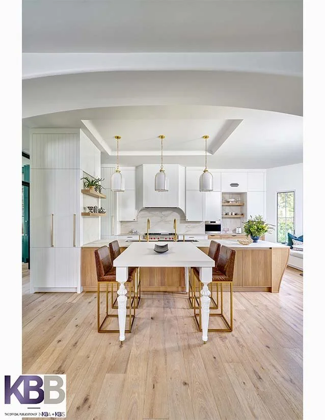 Modern open-concept kitchen with white cabinetry, pendant lights, a kitchen island with bar stools, wooden flooring, and a large window.