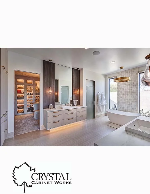 Modern bathroom with white walls, a bathtub near a window, a double vanity with two mirrors, pendant lights, and a walk-in closet with built-in shelves.
