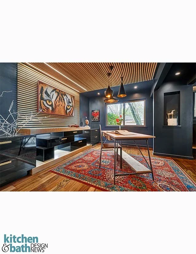 Modern living room with a tiger artwork, wooden slat ceiling, black wall, and large window with a view of trees, decorated with a colorful patterned rug and black furniture.