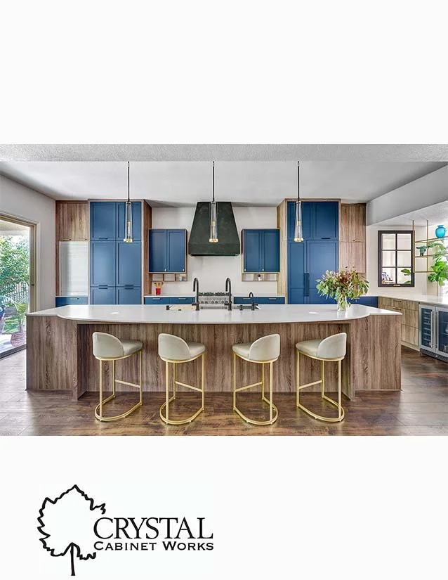Modern kitchen with blue cabinets, a large island with white countertop, beige bar stools, and pendant lights.